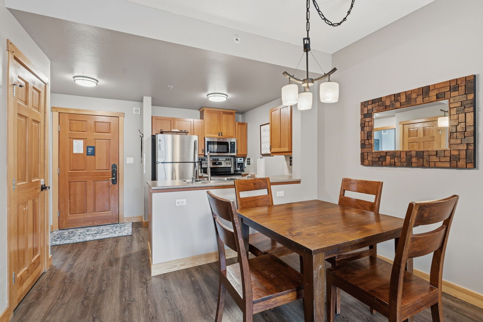 A modern kitchen with wooden cabinets, stainless steel appliances, and a dining area with a wooden table and chairs.