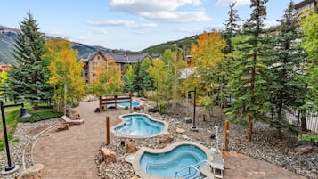 Un resort con zona de piscina, terraza de madera y vistas a la montaña.
