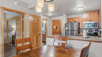A modern kitchen with wooden cabinets, stainless steel appliances, and a dining area with a wooden table and chairs.