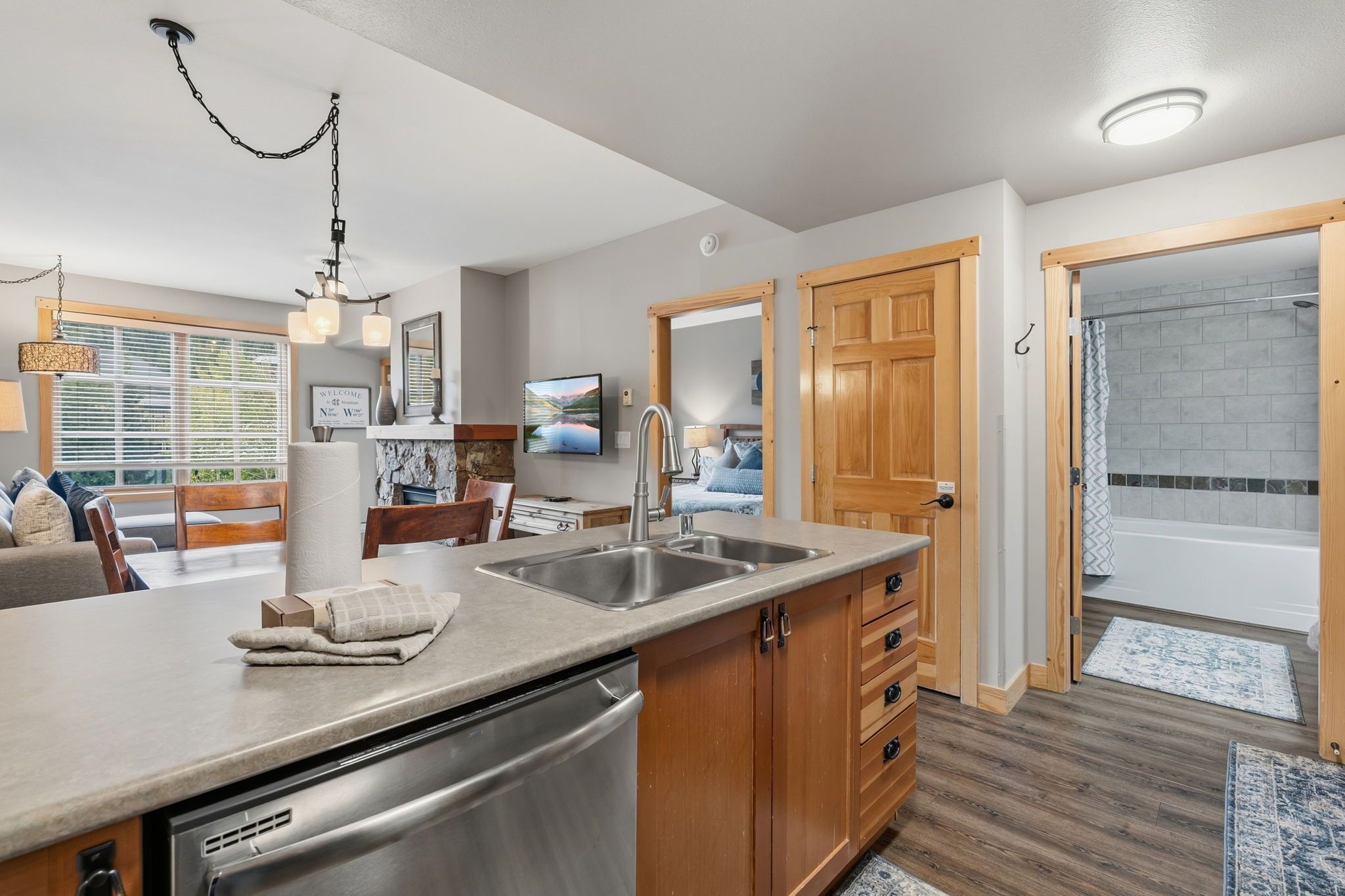 A modern kitchen with a stainless steel dishwasher, wooden cabinets, and a large island with a sink.