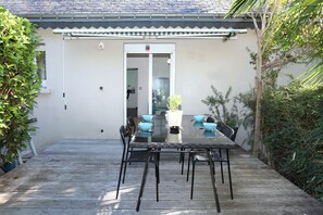 A patio with a glass-top table and chairs, surrounded by greenery. - Loargann ker Pondi - Maison pour 6 (Pontivy)