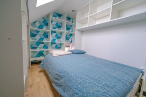 Ein Schlafzimmer mit einem Bett, einem weißen Kleiderschrank und einer Wand mit geometrischem Muster.