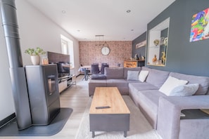 Ein modernes Wohnzimmer mit einer Eckcouch, einem Holztisch und einem Kamin.
