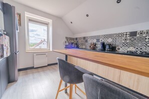 A modern kitchen with a wooden countertop, a window with a view, and patterned backsplash. - La Maison des Salines - Proche de la Gare (Varangéville)
