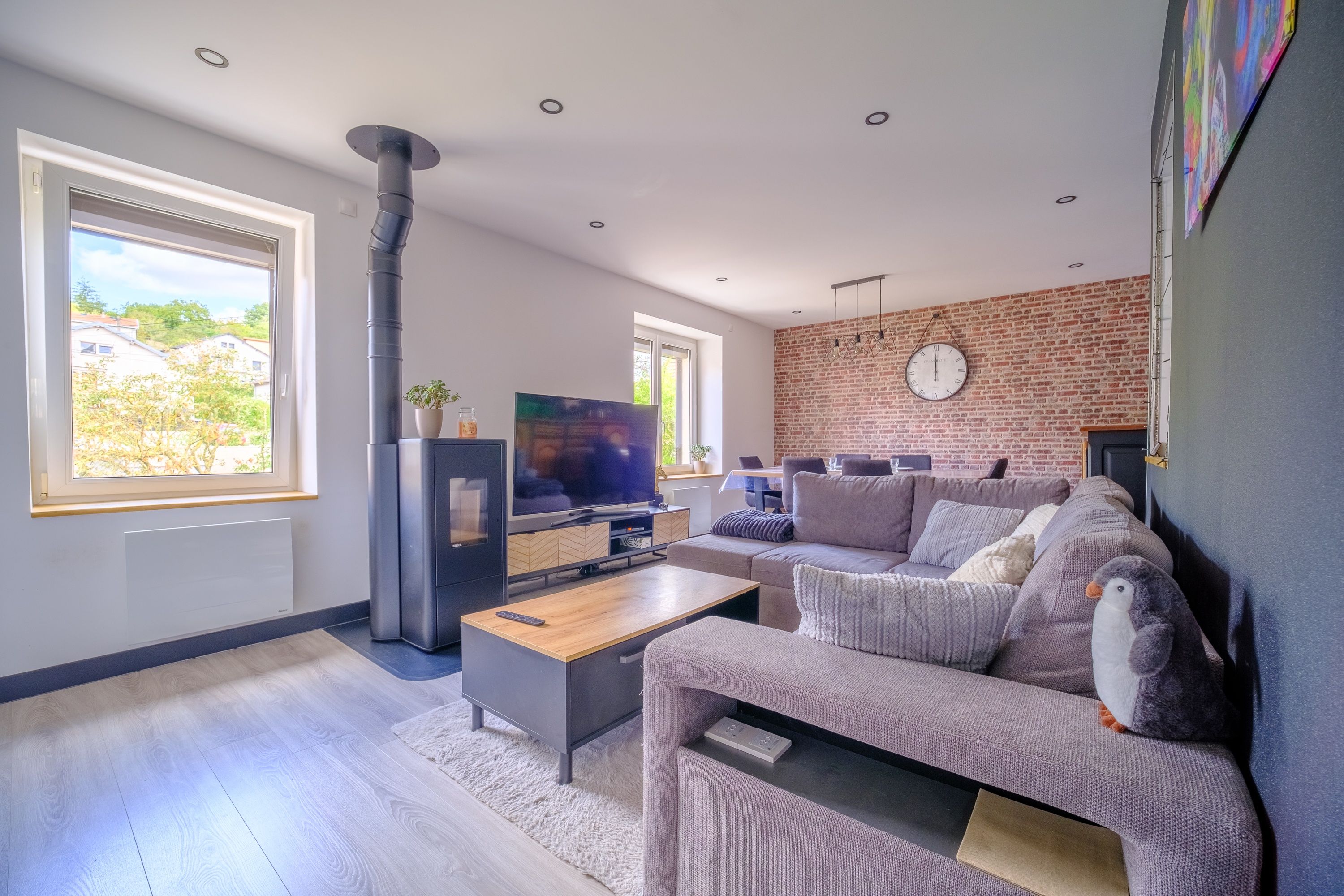 Ein modernes Wohnzimmer mit Kamin, Fernseher, Sofa und einer Ziegelwand.