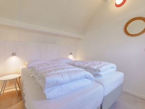 A neatly made bed with pillows and a small white stool beside it. - Holiday Apartment With 2 Bedrooms (Callantsoog)