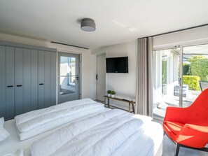 Ein Hotelzimmer mit einem Bett, einem Fernseher, einer Schiebetür und einem roten Sessel.