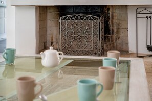 A room with a glass table, several mugs, a white teapot, and a decorative metal screen in front of a fireplace. - Ker-eole - A côté du Port de la Trinité (La Trinite-sur-Mer)