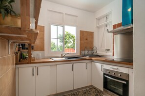 Eine moderne Küche mit weißen Schränken, einem Edelstahlbackofen und einem Fenster mit Blick ins Grüne.