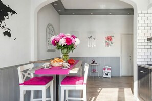 A dining area with a table set for two, a vase of flowers, and a small side table with a basket of bread. - Peonies House-Vatican: A Chic and Peaceful Premium Retreat (Roma)