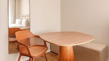 Ein modernes, minimalistisches Zimmer mit einem Holztisch, zwei Stühlen, einer Couch und einem großen Spiegel.