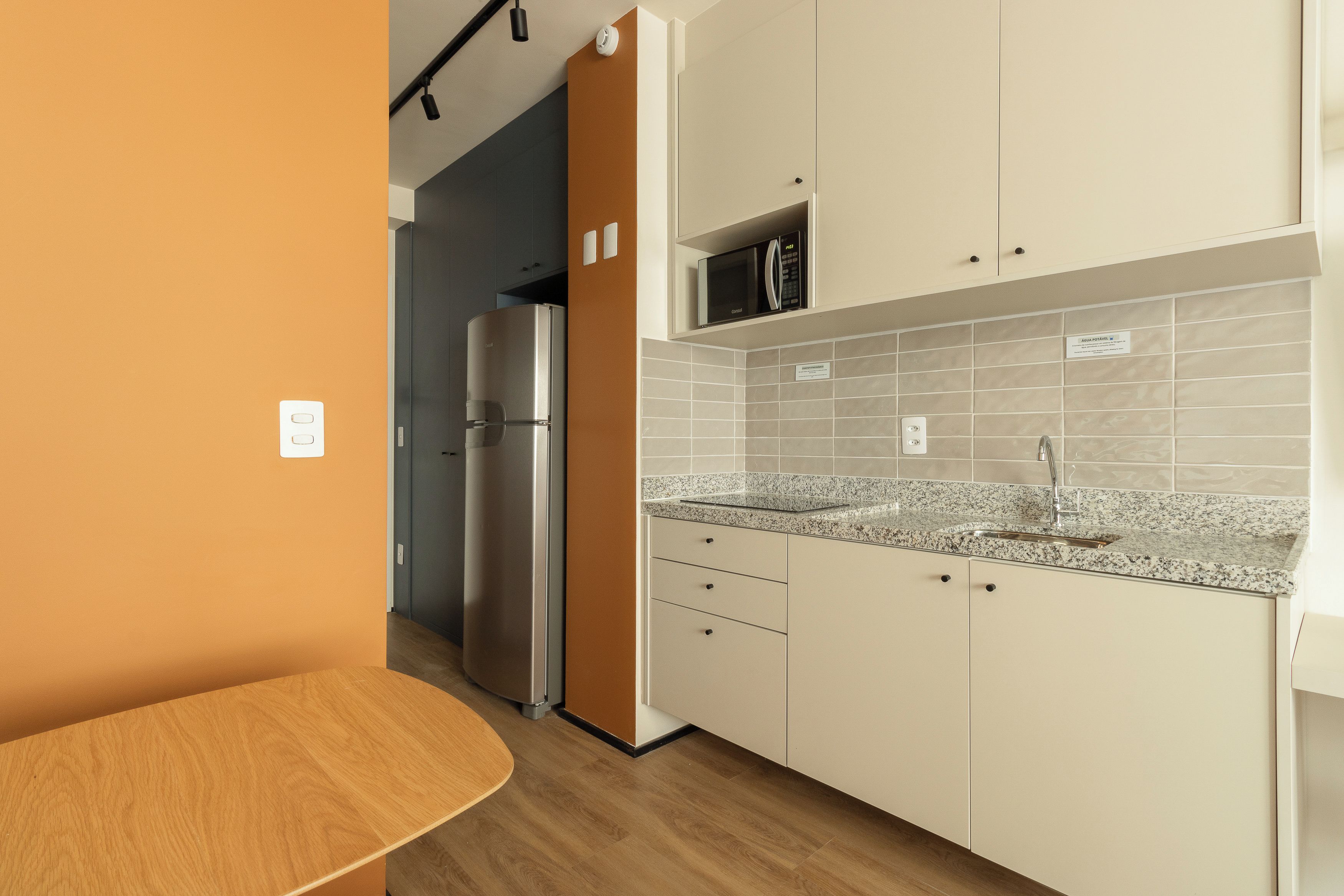 A modern kitchen with a built-in microwave, stainless steel refrigerator, and granite countertop.