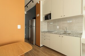 A modern kitchen with a built-in microwave, stainless steel refrigerator, and granite countertop. - Coronel by Bhomy (São Paulo)