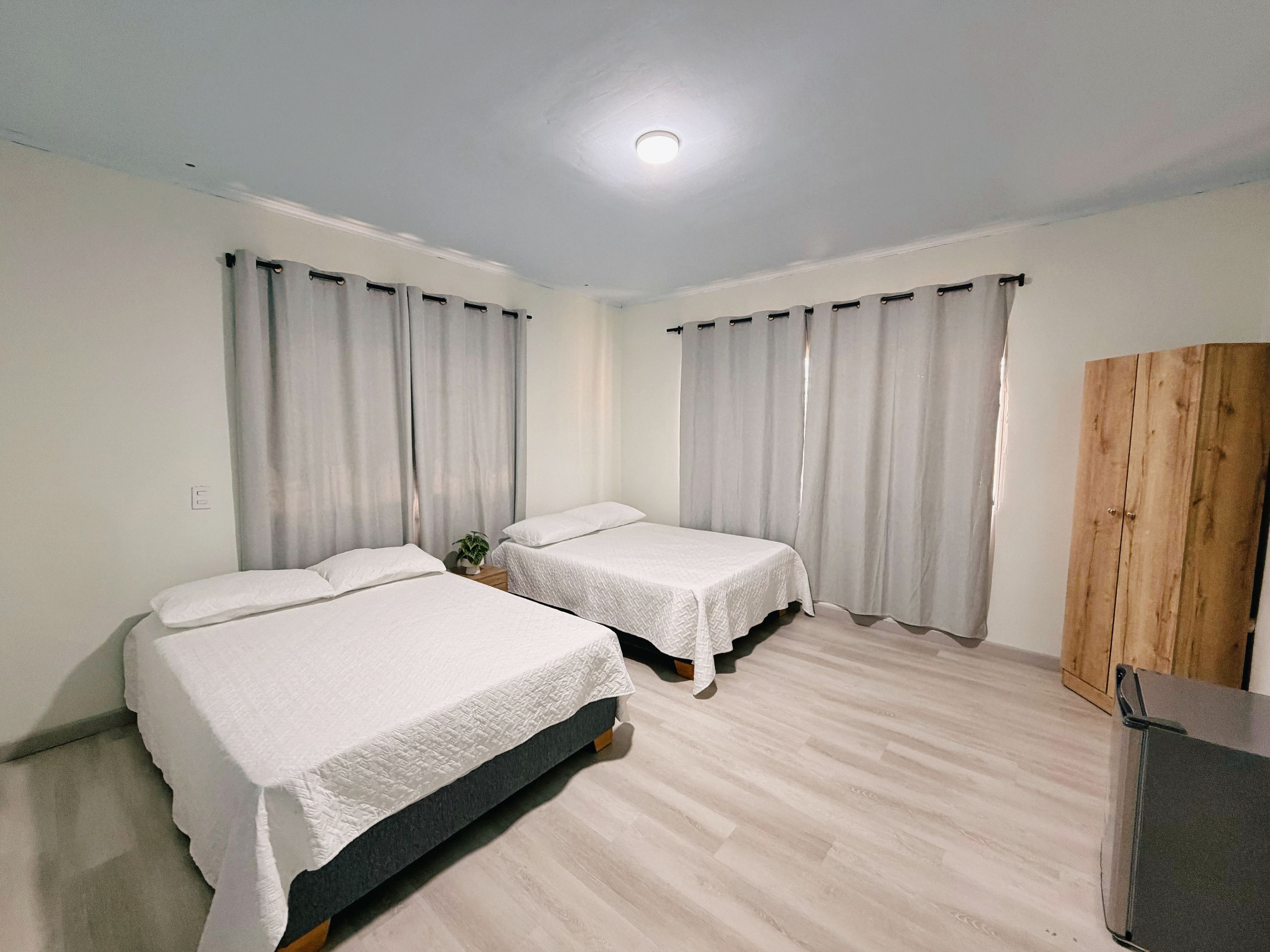 Une chambre d’hôtel avec deux lits, une armoire en bois et une petite table.