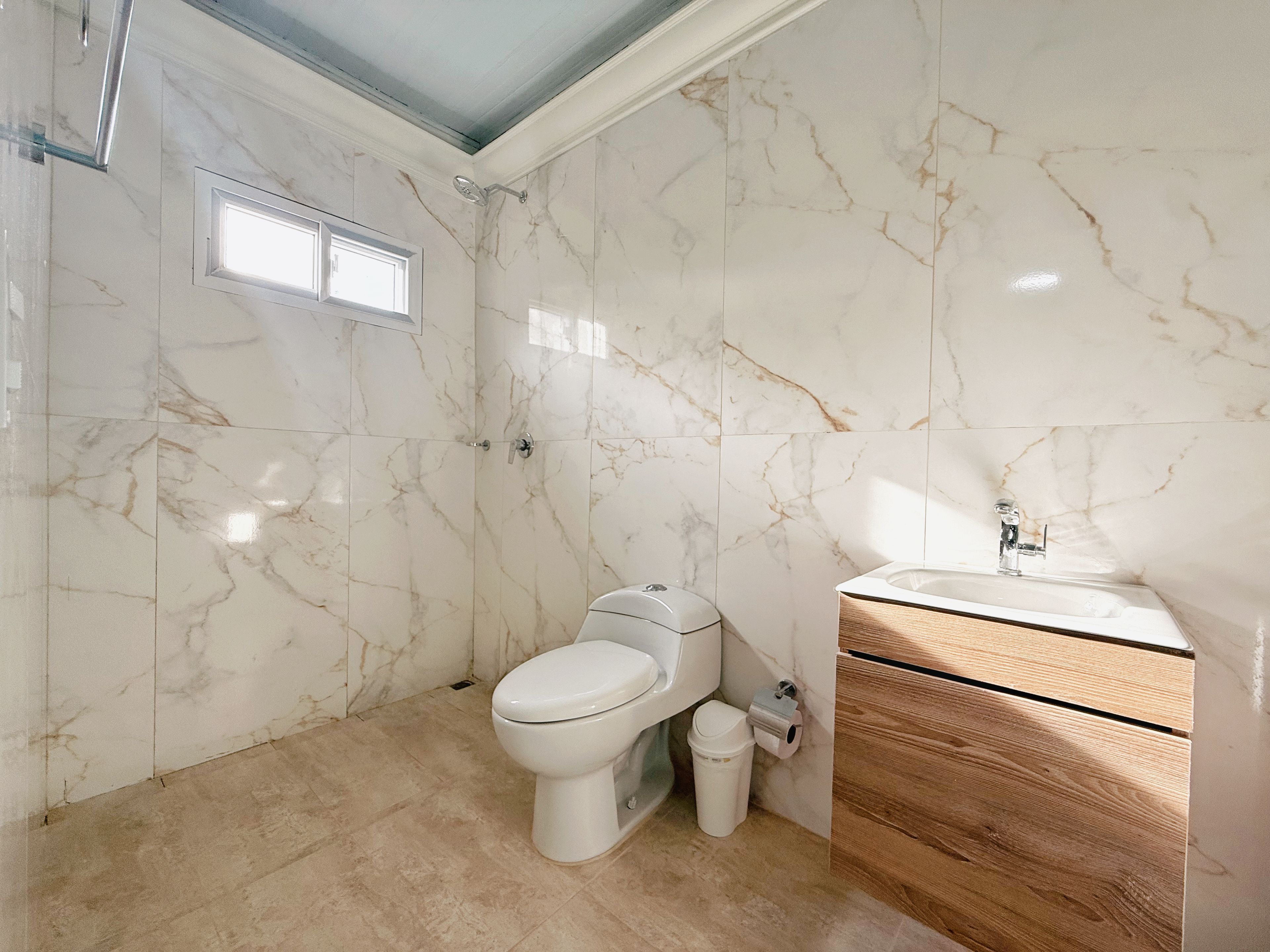 A bathroom with a toilet, a shower, and a sink.