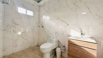 A bathroom with a toilet, a shower, and a sink.