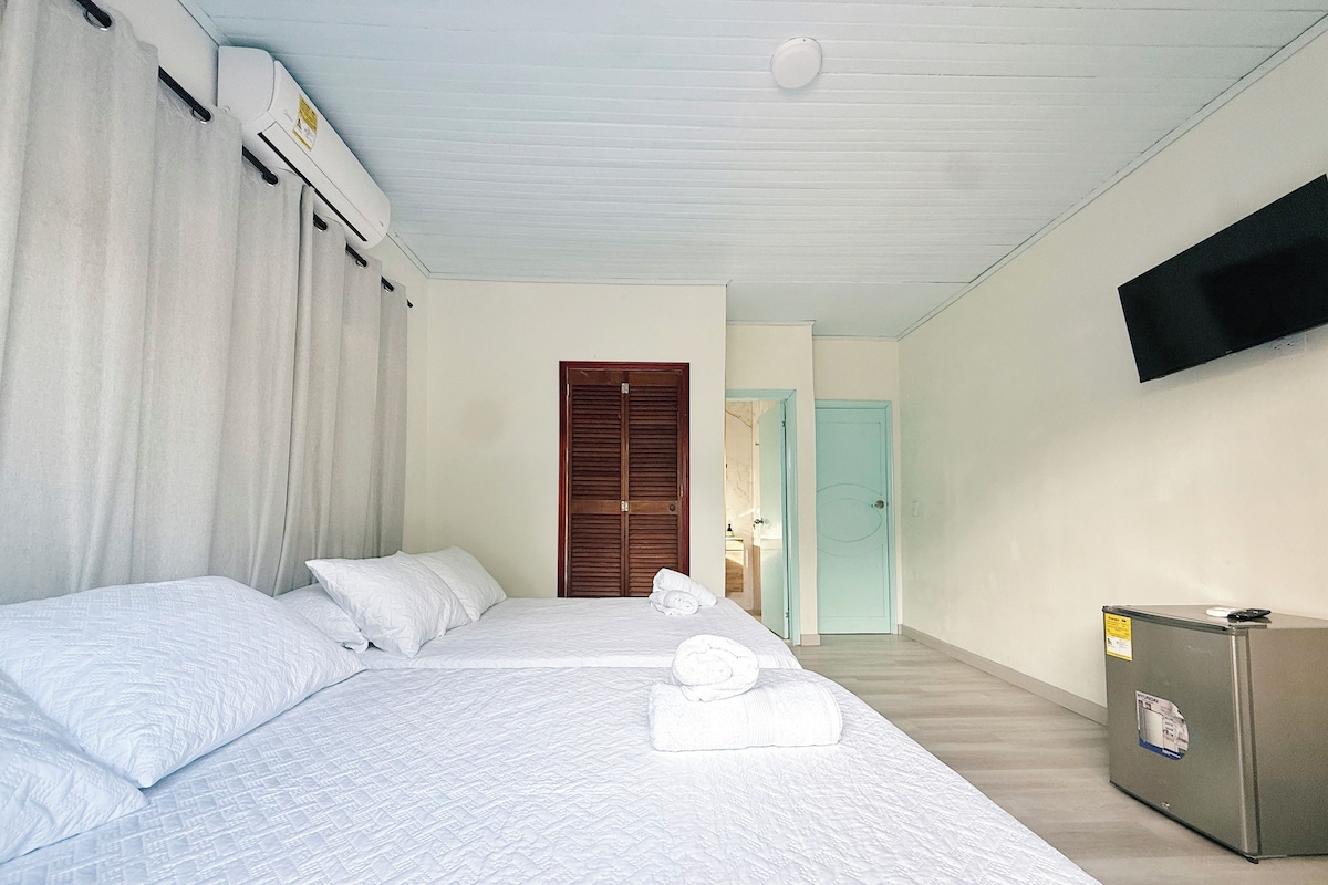 A hotel room with two beds, a TV mounted on the wall, and a minibar.