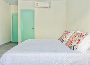 Habitació d'hotel amb un llit, una porta i un aparell d'aire condicionat.