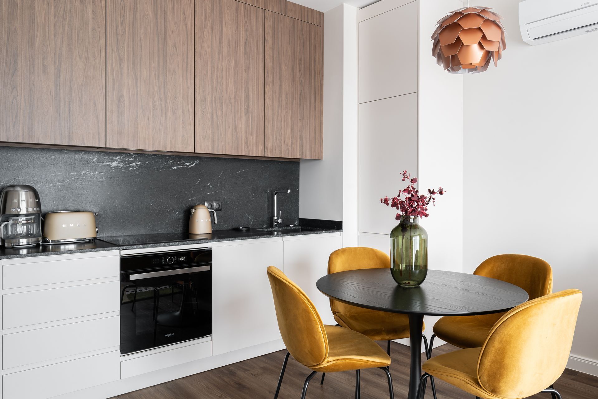 Een moderne keuken met een zwart aanrecht, roestvrijstalen apparatuur en houten kastjes.