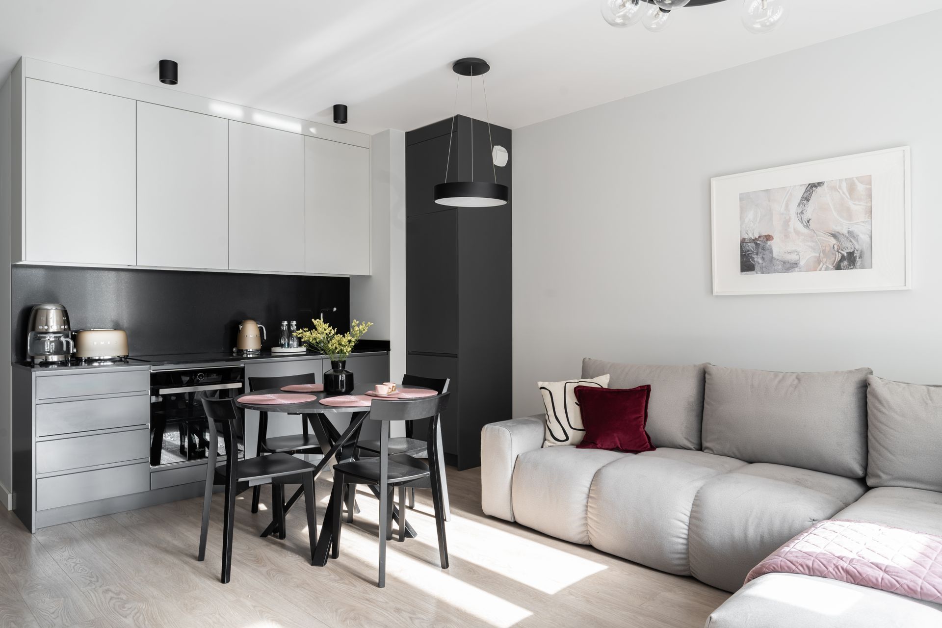 A modern kitchen with a dining area, a sofa, and a framed artwork on the wall.