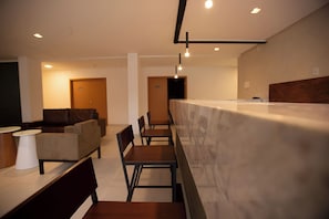 A modern hotel lobby with a reception desk, seating area, and a staircase leading to another floor. - Modern Space Near Araripina Botanical Garden and Araripe Regional Airport (Pernambuco)