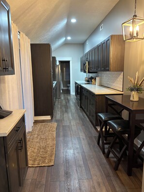 A modern kitchen with dark wood cabinets, a central island with stools, and a hanging light fixture. - Long Term Fully Furnished Country Farmhouse Ranch w/ pond in Rock Creek, Ohio (Rock Creek)