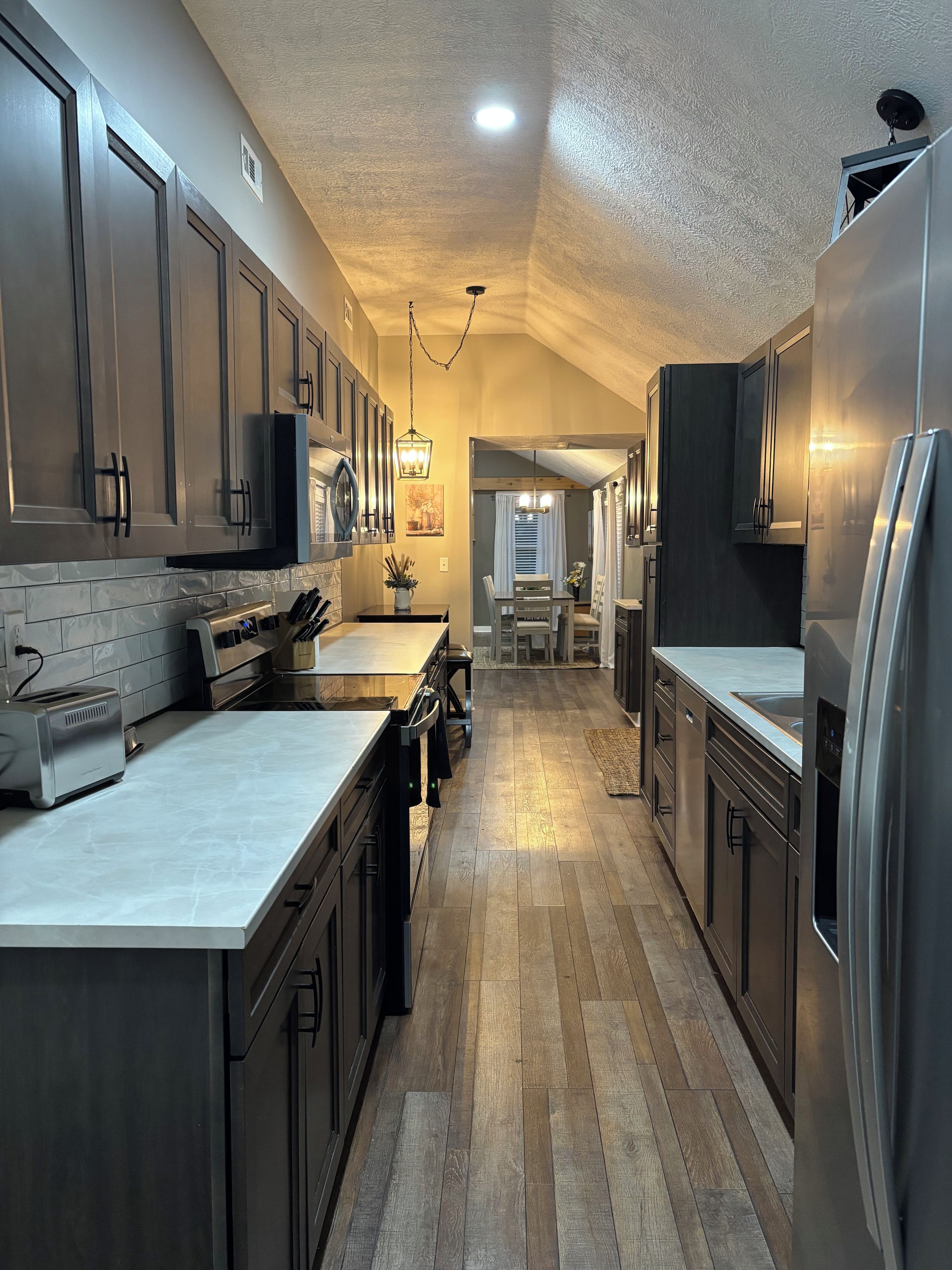 A kitchen with wooden flooring, stainless steel appliances, and a central island.