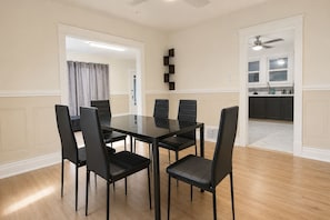 A dining area with a rectangular table and six chairs, a kitchen in the background, and a ceiling fan. - 2BR Lower Unit Near Niagara Falls | Free WiFi (Niagara Falls)