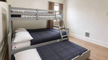 A bunk bed with a ladder, two pillows, and a window with curtains.