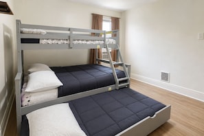Een stapelbed met een ladder, twee kussens en een raam met gordijnen.