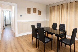 A dining area with a rectangular table and six chairs, a hallway leading to another room, and three wall-mounted decorative panels. - 2BR Upper Unit Near Niagara Falls | Free WiFi (Niagara Falls)