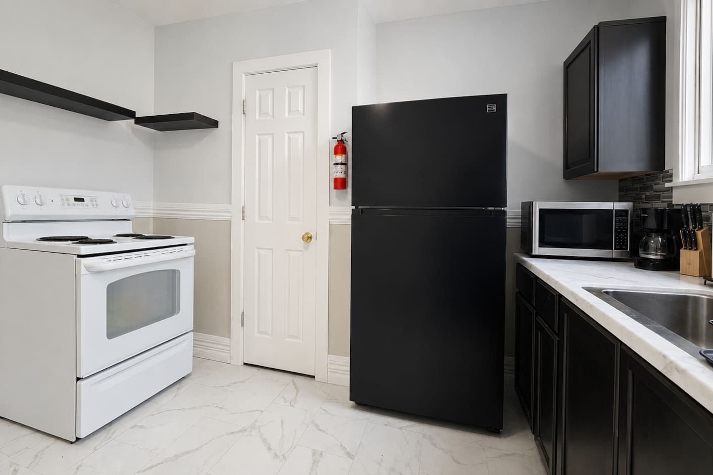 A kitchen with a white stove, black refrigerator, and a microwave.