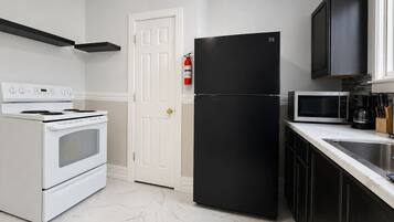 A kitchen with a white stove, black refrigerator, and a microwave.