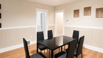 A conference room with a glass table, black chairs, wooden flooring, and decorative wall panels.
