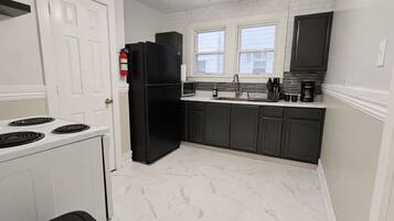 A kitchen with a white stove, black refrigerator, and dark cabinets.
