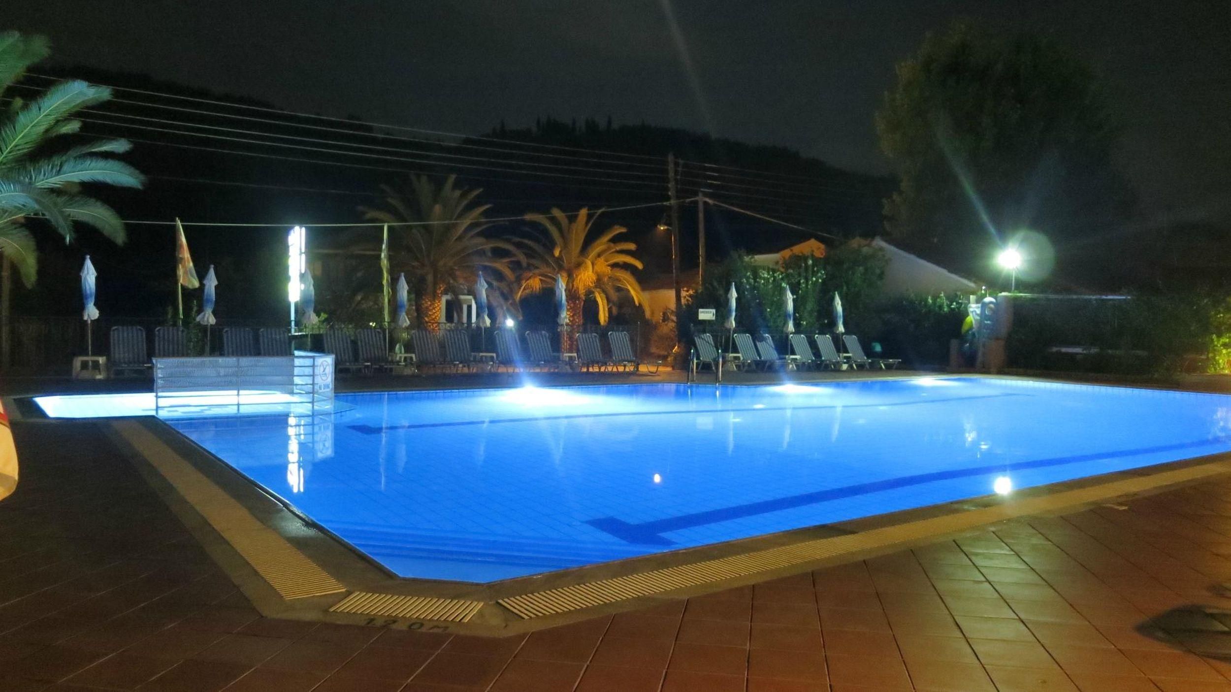 Une piscine la nuit, avec des chaises longues et des parasols.