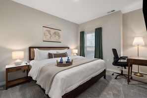 A hotel room with a large bed, a desk, a chair, a nightstand, and a wall-mounted globe. - New Albany 2BR Near Intel Easton Pets OK (Westerville)
