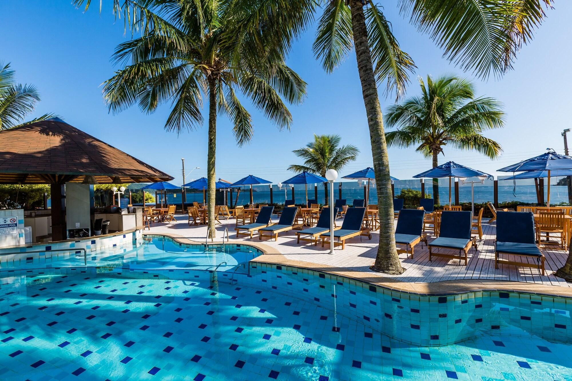 A pool area with lounge chairs and umbrellas, surrounded by palm trees.