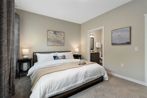 A hotel room with a bed, bedside tables, a nightstand, a mirror, a painting, and a bathroom visible through an open door. - The Nook New Albany Area Balcony (Westerville)