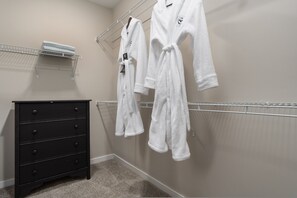 A hotel room with a black dresser, a towel rack with white towels, and a white robe hanging on the wall. - The Nook New Albany Area Balcony (Westerville)
