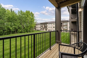 A balcony with a view of a multi-story building and a grassy area. - The Nook New Albany Area Balcony (Westerville)