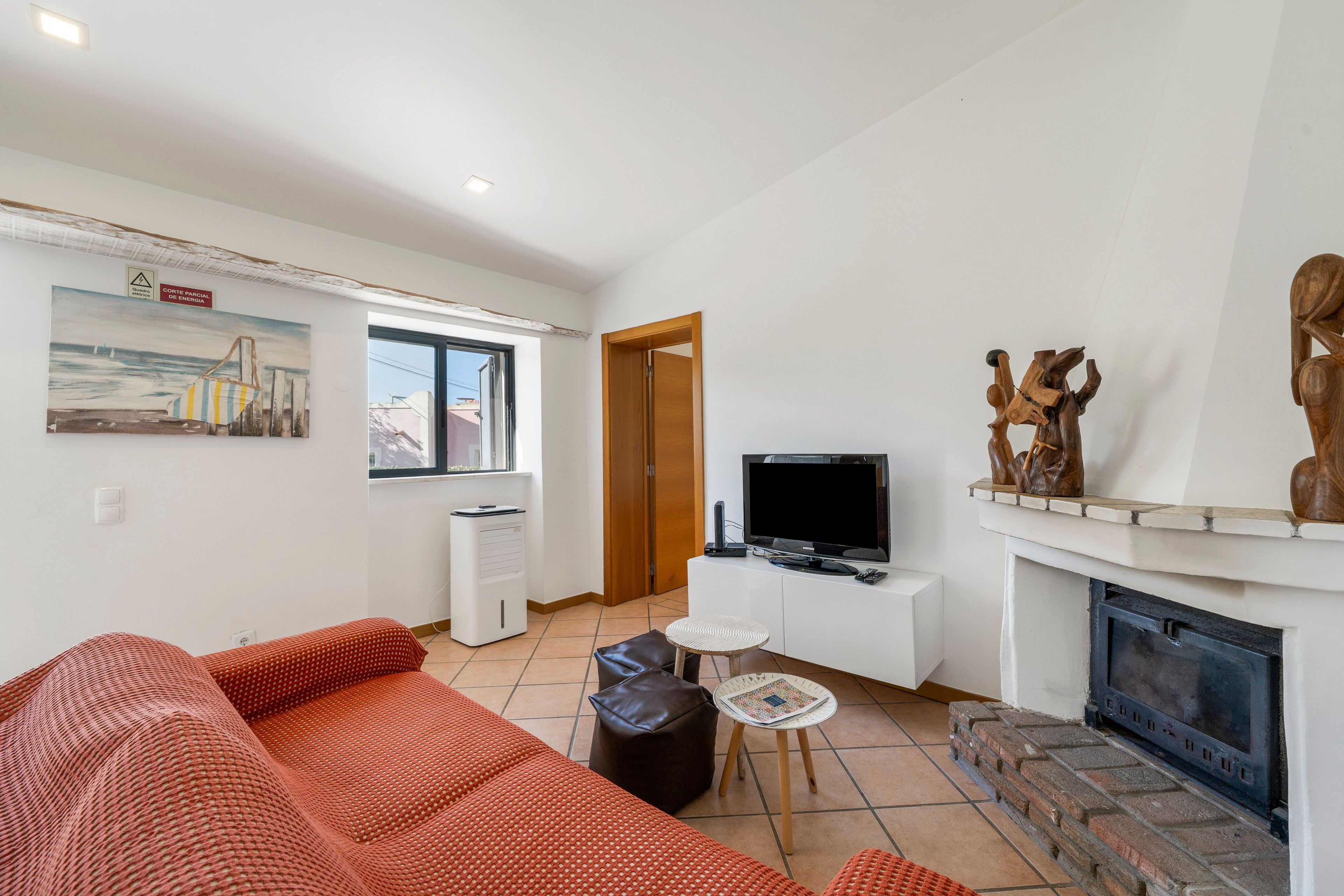 A living room with a sofa, a television, a fireplace, and a painting on the wall.