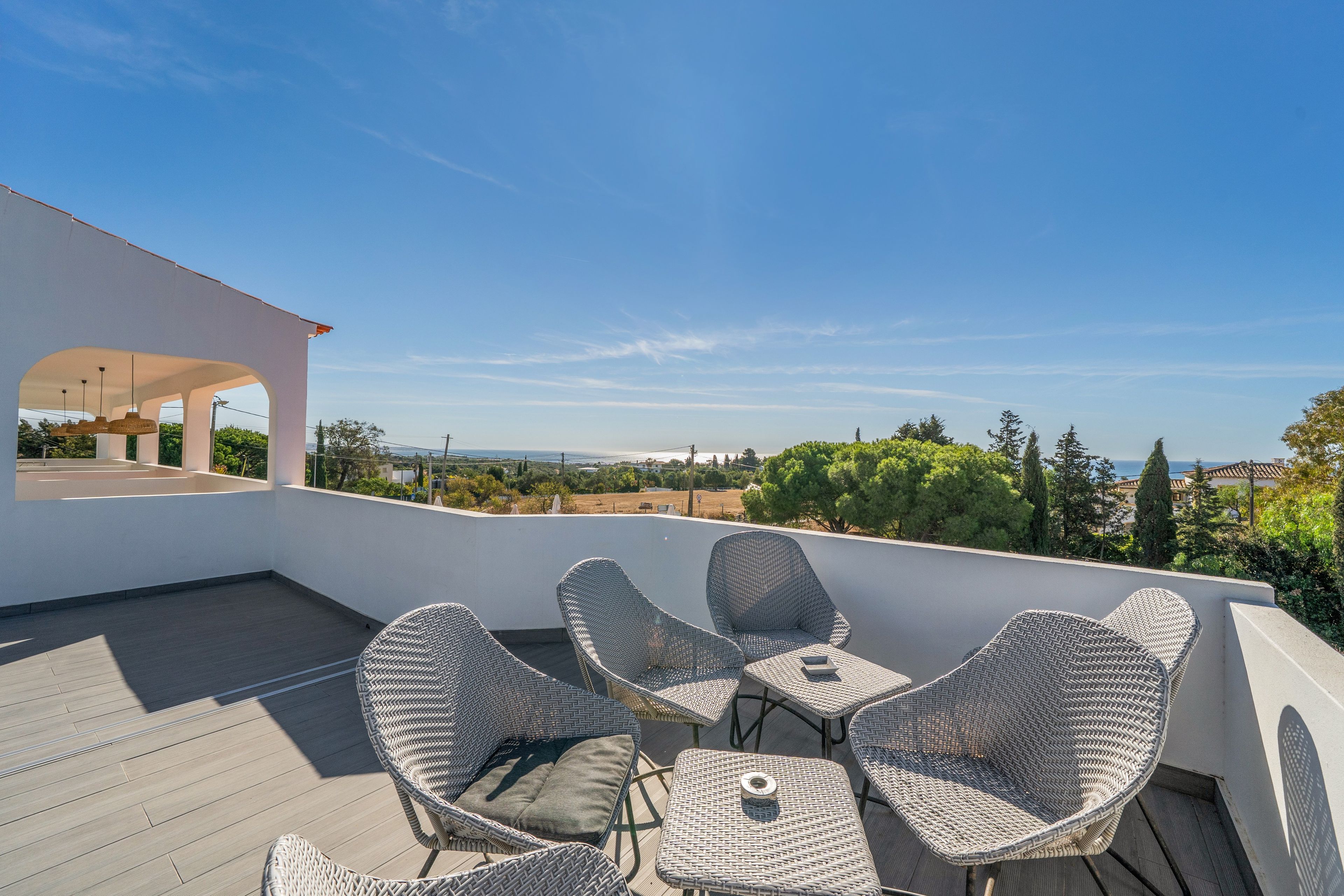 Une terrasse sur le toit, aménagée avec des meubles en osier et offrant une vue sur le paysage.