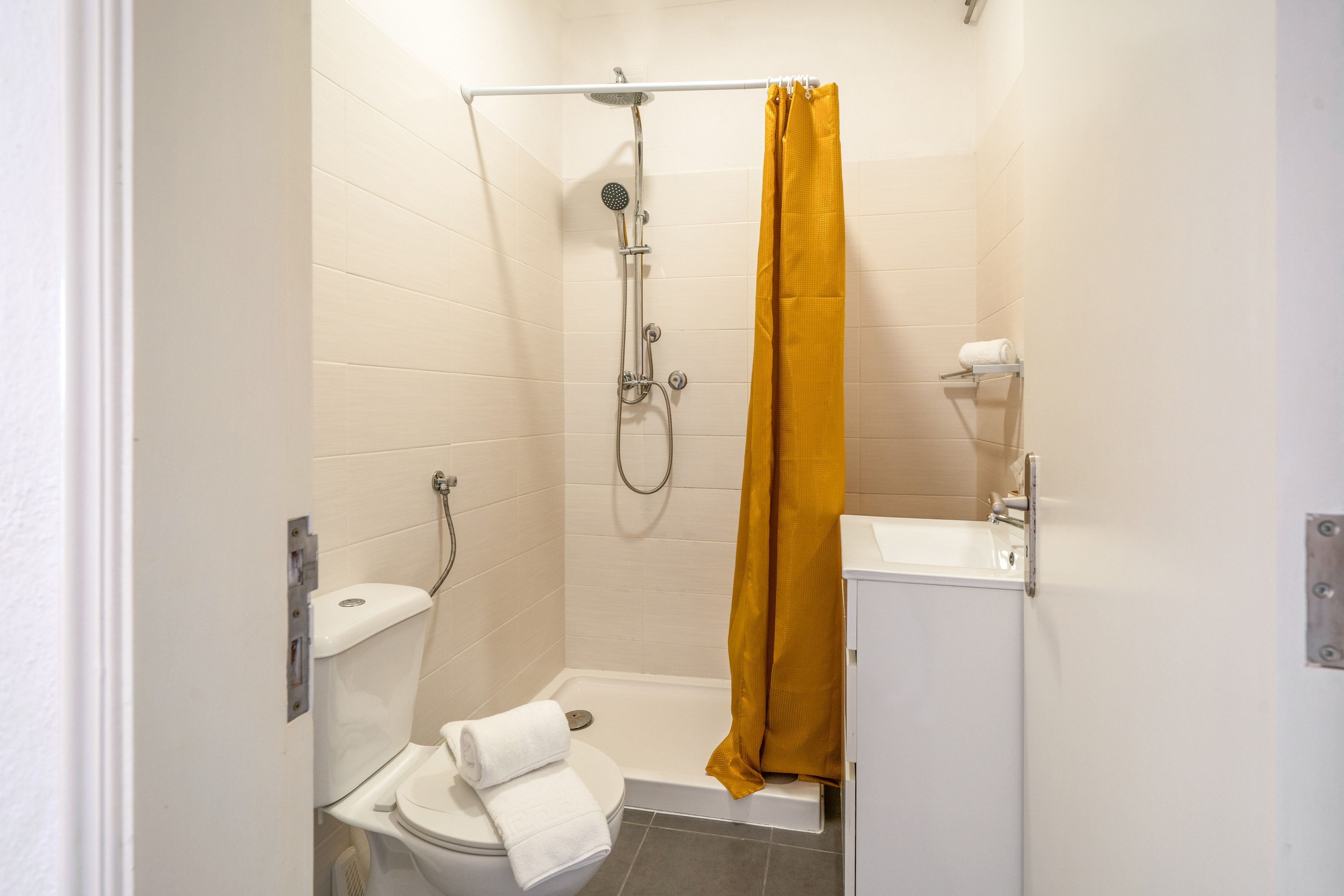 Ein kleines Badezimmer mit Dusche, Toilette und Waschbecken.