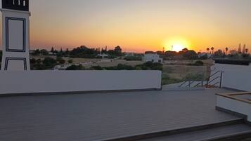 Eine Dachterrasse mit Blick auf einen Sonnenuntergang über einem Wohngebiet.