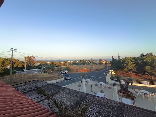 Vista de una carretera con vehículos, un paso de peatones y un edificio con terraza.