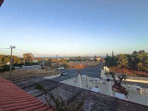 A view from a balcony overlooking a road with cars, a bridge, and a restaurant with outdoor seating.
