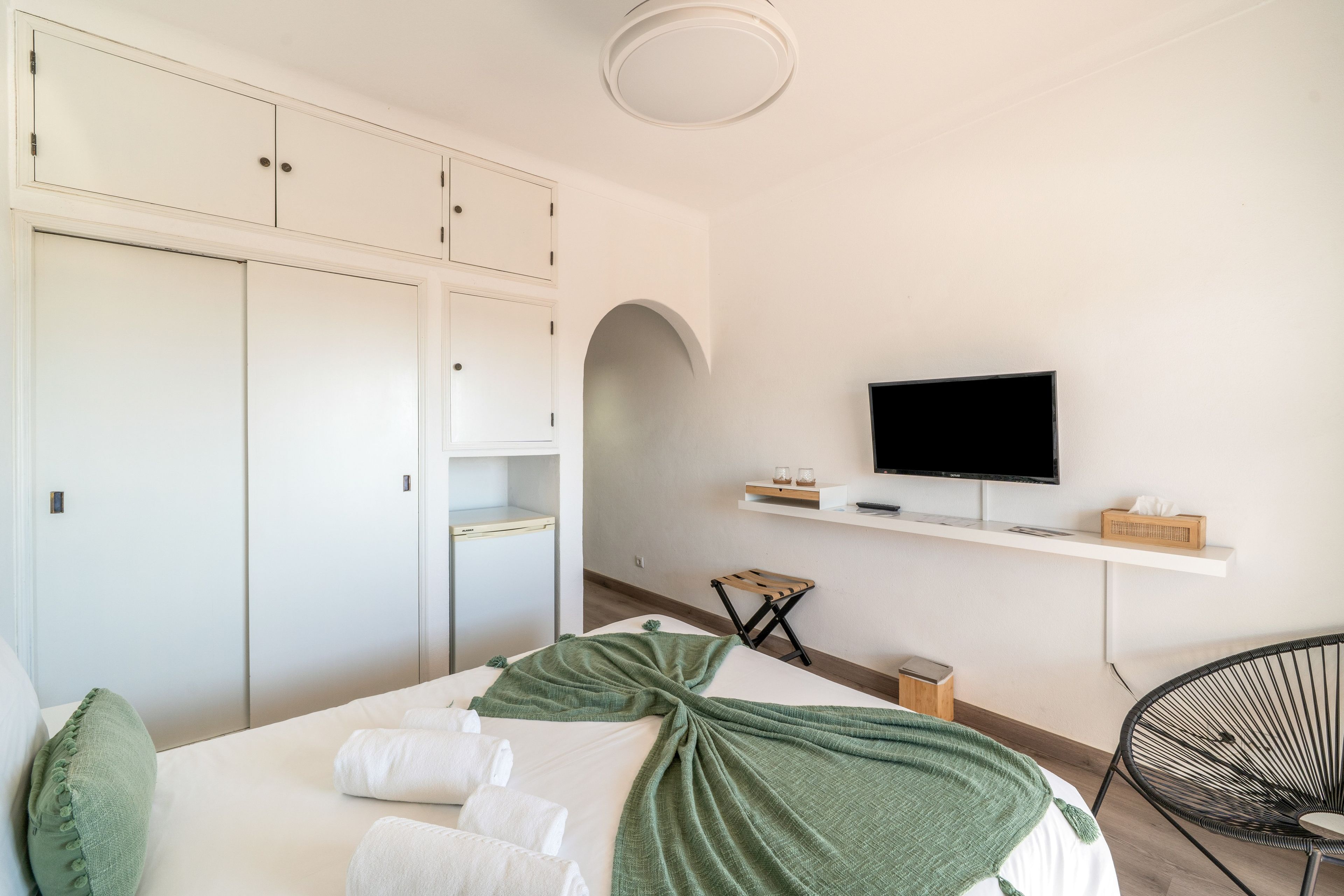 Ett hotellrum med en säng, en tv, ett litet bord och en stol.