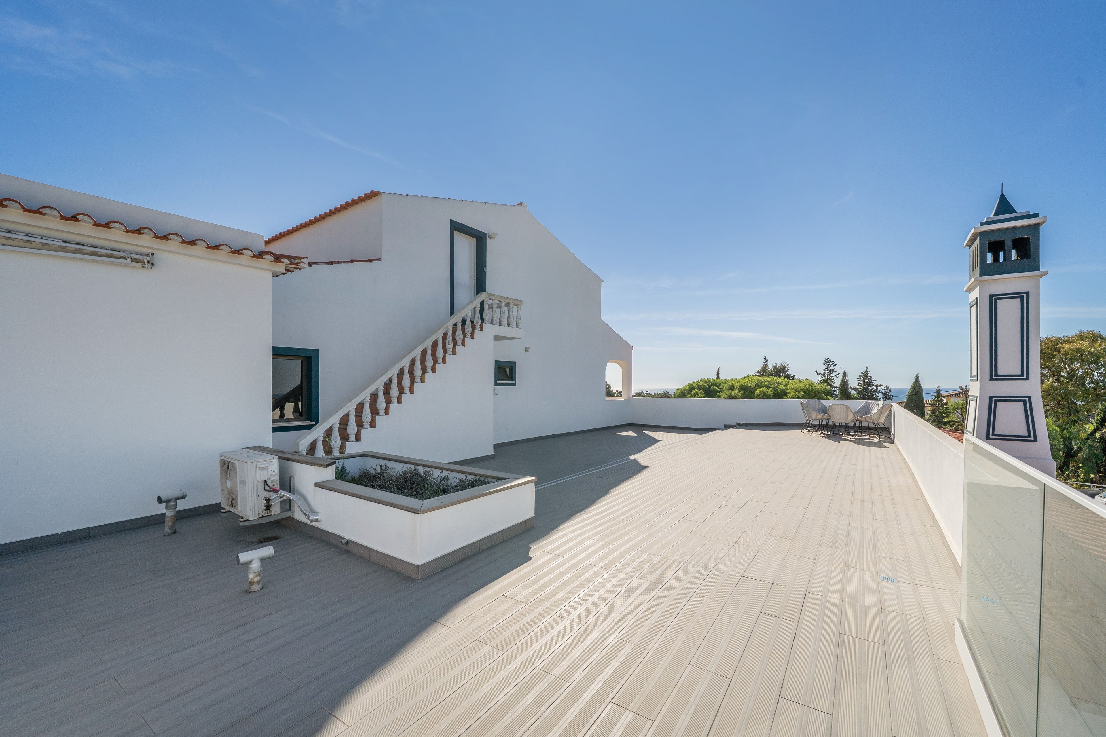 Eine Dachterrasse mit Treppe, einem kleinen Tisch und Blick auf das Meer.