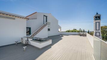 Eine Dachterrasse mit Treppe, einem kleinen Tisch und Blick auf das Meer.